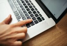 Ruka na klávesnici notebooku při práci s dokumenty