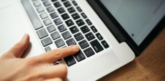 Ruka na klávesnici notebooku při práci s dokumenty
