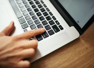 Ruka na klávesnici notebooku při práci s dokumenty